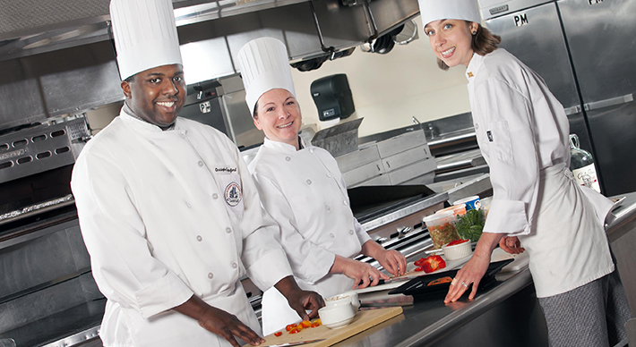 a group of students in a professional kitchen cooking