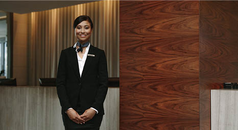 A professionally dressed woman standing in front of a reception desk