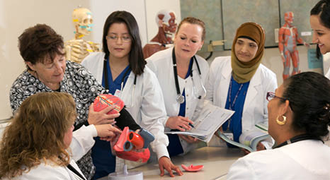 Nursing students gathered around listening to explanation by an instructor